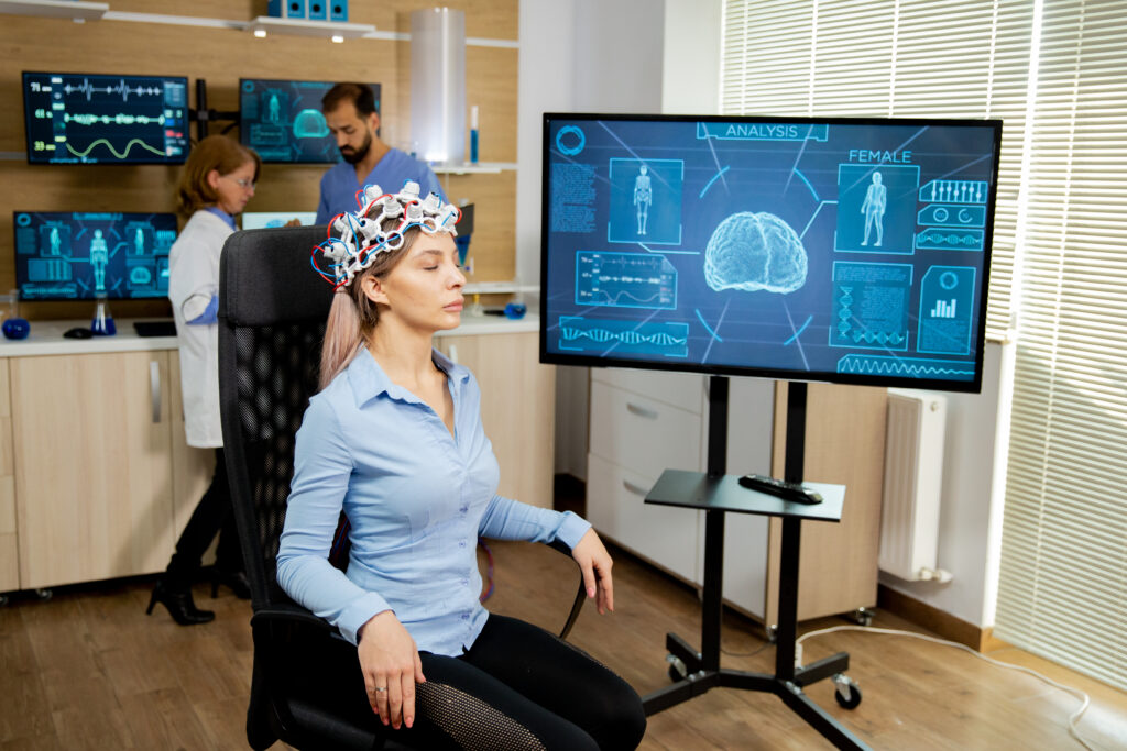 patient woman with head scanning device and brain activity is seen on screen